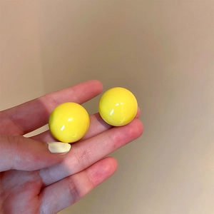 Close-up of vibrant yellow round acrylic earrings with a smooth polished glossy finish