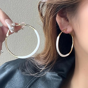 Minimalist gold hoop earrings with white enamel finish shown on a fashion model