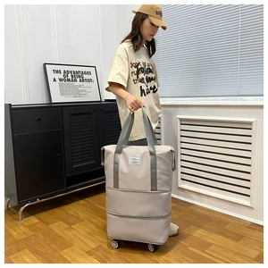 Detail showing foldable beige travel bag with expansion layers and wheels for storage