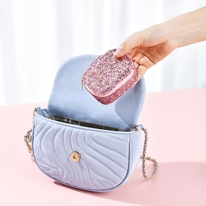 Portable pink glitter jewelry box being placed into a bag showing compact travel size