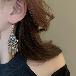 Detail view of ethnic crescent earrings with floral engravings and metallic tassels