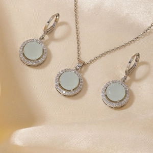 Schmuckset aus Silber mit hellgrünen Zirkonsteinen auf goldenem Satinstoff im Detail