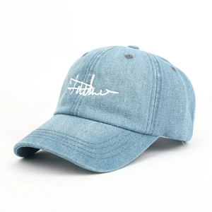 Close-up of artistic white letter embroidery on light blue washed denim baseball cap