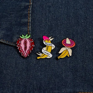 Detailed close-up of fruit-shaped enamel pins on dark blue denim fabric background
