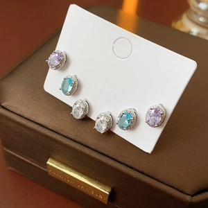 Macro view of three pairs of oval-cut zircon earrings in purple, blue and white colors