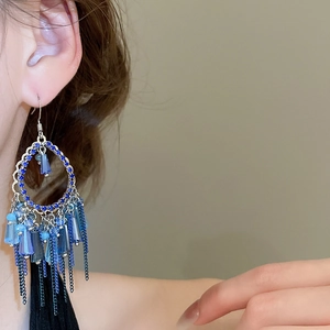 Close-up of bohemian blue crystal earrings with gradient metal tassels on model