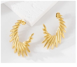 Detailed close-up of gold wing-shaped stud earrings with sunburst texture on stone