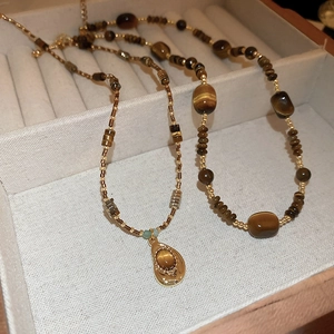 Collier en œil de tigre irrégulier avec perles dorées dans un coffret à bijoux
