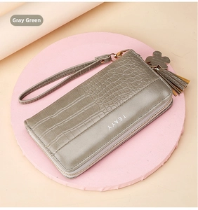 Detail of grey green crocodile pattern leather wallet with wristlet and floral tassel