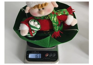 Close-up showing the weight of a Christmas parachute elf ornament on a digital scale