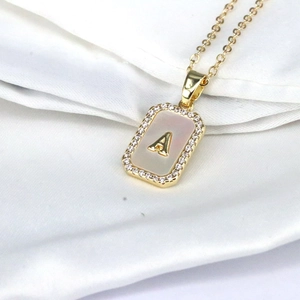 Macro shot of 18K gold letter A pendant with shell inlay and cubic zirconia stones