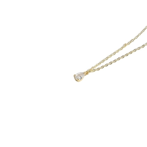 Minimalist gold necklace with a clear teardrop pendant shown on a white background