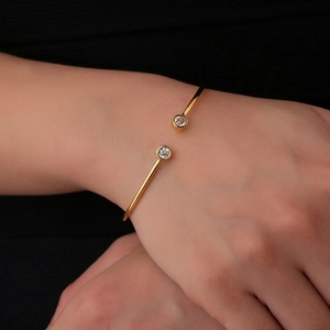 Minimalist gold open cuff bracelet with sparkling cubic zirconia on a female model's wrist