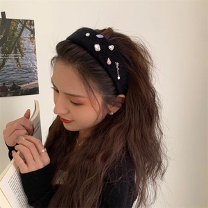 Elegant black plush headband with rhinestones and pearls worn by a model in soft lighting