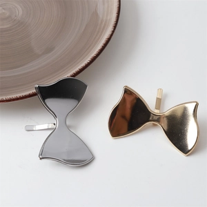 Detailed view of gold and silver metallic bow hair clips with polished mirror finish