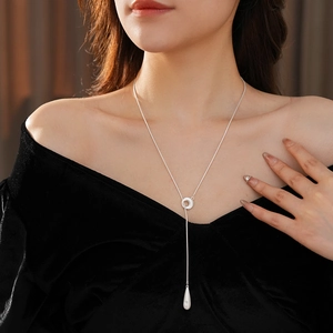 Close-up of silver drop pendant necklace worn by a model for a stylish commute look