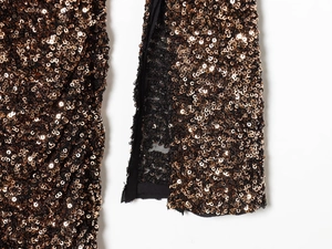 Macro view of bronze sequin fabric with split detail on shoulder pad dress