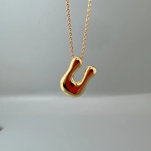 Macro view of a polished gold letter U initial pendant on a delicate chain necklace