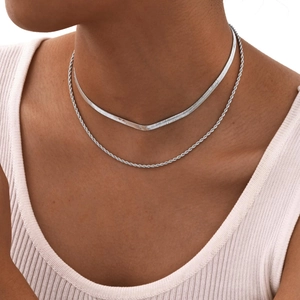 Detail of silver double-layered snake and twist chain necklaces on model neck