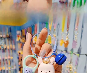 Detail of cute resin rabbit keychain with blue bell, gold crown and pearl charm