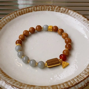 Close-up of beaded bracelet with fluorite stones and Fu character gold pendant