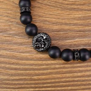 Close-up of black matte beads bracelet featuring a lion head and dark gemstones