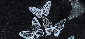Macro detail of laser-cut butterfly PET sticker with silver holographic finish on black
