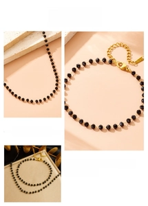 Macro detail of gold stainless steel lobster clasp and black faceted beads on necklace