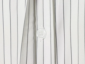 Macro shot of vertical striped fabric texture and a fine white button on a dress