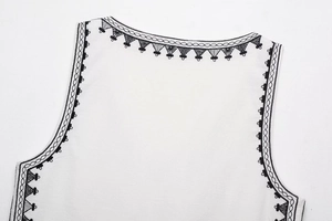 Detailed view of black geometric embroidery on white cotton neckline with fine stitching