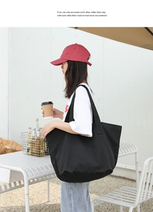 Outdoor shot of a model wearing a large black washed canvas tote bag for casual daily use