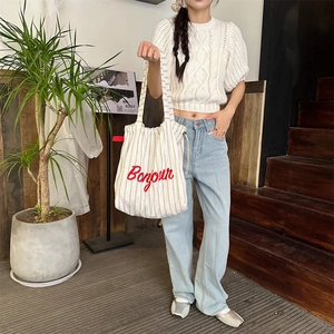 Detailed embroidery of red Bonjour text on a striped canvas tote bag close-up
