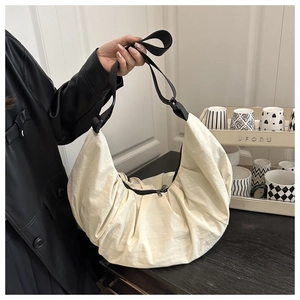 Détail du sac croissant plissé blanc crème avec bandoulière réglable noire et zip argent