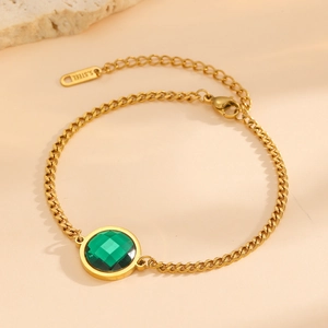 Detailed macro view of 18K gold plated stainless steel bracelet with green stone charm