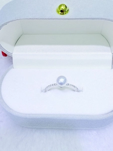 Macro view of a 6-7mm round pearl ring with pavé-set diamonds in a velvet gift box