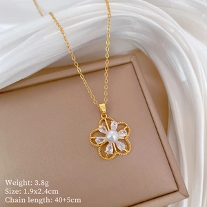 Detail of gold hollow flower necklace with white pearl and zircon on beige jewelry box