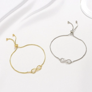 Detail of gold and silver infinity bracelets with crystals on white silk background