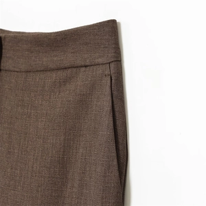 Détail du pantalon marron montrant la couture de taille et la poche latérale
