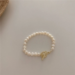 Detail of freshwater pearl bracelet with a golden OT toggle clasp on beige background