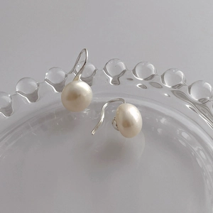 Detailed shot of white freshwater pearl earrings on embossed glass tray with S925 stamp