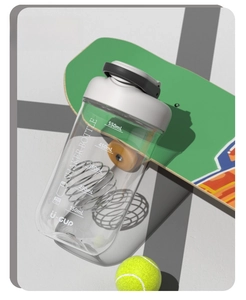 Detailed view of 750ml protein shaker bottle with scale, metal ball, and tennis ball