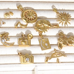 Collection of gold celestial and hobby charms like sun, moon, and camera on jewelry tray