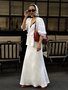 Detail of white two-piece set featuring lace-up puff sleeve top and high waist maxi skirt
