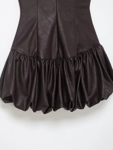 Vue détaillée de l'ourlet plissé en similicuir sur une robe tendance marron foncé