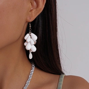 Close-up of stylish white acrylic teardrop beaded earrings worn on a female model