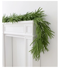 Detail of realistic Norfolk pine garland on white mantel with lush green needles