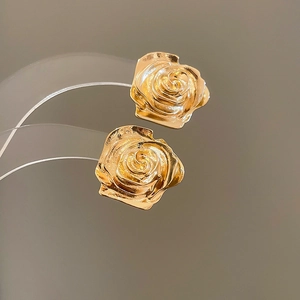 Dettaglio di orecchini a rosa 3D dorati su supporto con petali in metallo lucido