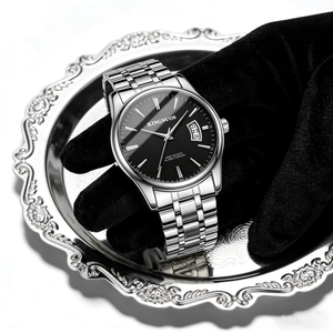 Macro shot of silver stainless steel watch with black dial on an ornate silver tray