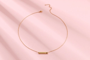 Detail of gold horizontal bar necklace with inlaid heart on elegant pink fabric
