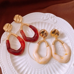 Detailed view of vintage oval earrings with amber and cream marble textures on a plate